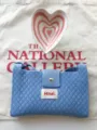 Detail view of the blue knitted crossbody bag featuring a magnetic flap and woven label. - Sky Blue
