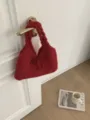 Detail van een rode gebreide okseltas met strik die aan een witte deur hangt - 28*40cm / Rood