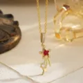 Close-up of vintage gold shooting star necklace with red and white zircon accents - Pendant Necklace (80495) / Red