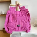 Detail view of bright pink pleated knitted handbag featuring unique 3D textured design. - Wave Texture Style / Rose Red