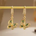 Elegant close-up of vintage hollow butterfly earrings with emerald green zircon stones - Vintage Butterfly Style (80491) / Earrings / Gold Tone (Emerald Green Zirconia)