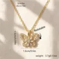 Rotating gold butterfly pendant necklace with zircon details on fabric background - Butterfly Flower Rotatable (80342)