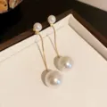 Macro view of elegant pearl tassel drop earrings featuring gold-tone thin chains - 7cm / Gold White