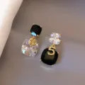 Detail view of asymmetric earrings with black and clear crystals, gold clover and number 5. - Asymmetric Square Number 5 Style (E3109) / Gold