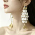 Elegant fish-shaped tassel earrings with iridescent shell disks on an Asian model - Fish Shape Evil Eye Tassel Style / Gold White (E5311)