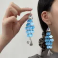 Close-up of vibrant blue fish-shaped acetate tassel earrings worn by an Asian model - Fish Shape Evil Eye Tassel Style / Silver Blue (E5311)