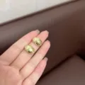Dettaglio di orecchini minimalisti a goccia in metallo dorato tenuti sulle dita - Stile Goccia Oro Specchio (E3130) / Oro