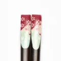 Vue détaillée du haut des baguettes en bois avec motifs floraux rouges et géométriques verts - Impression Ongle-Prune Plume Flèche (16 Long)
