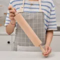 Rouleau à pâtisserie en hêtre naturel durable tenu par une personne en cuisine - Grande Taille 45x5.8cm / Blanc Cassé