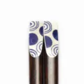 Nahaufnahme von dunklen Holzstäbchen mit blau-weißen geometrischen Spitzenmustern. - Nagel Druck-Blau Weiß Geometrisch (21 Kurz)