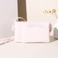 Minimalistische lichtroze PU-leren vierkante crossbodytas met een getextureerde kruisarcering. - Lichtroze