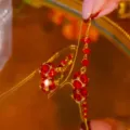 Close-up macro view of red crystal petal tassel earrings on a golden mirror surface - E3763 Gold Red Rhinestone (Tassel Petal Style)