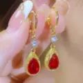 Close-up view of elegant gold drop earrings with teardrop red stones and crystals - Teardrop Pendant Style (E4160)