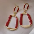 Close-up of elegant gold-toned geometric earrings with deep red enamel finish. - Irregular Geometric Trapezoid Style (E3212)