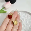 Elegant golden hoop earrings with Ankora red heart design shown on a person's hand - E4291 Wine Red (Vintage Gold Border Red Heart Hoop)