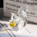 Detailed close-up of a faceted clear crystal squirrel figurine holding a yellow nut - Squirrel Figurine / Clear with Yellow