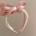 Detailed view of pink silk bow and faux pearls on a vintage style headband - Pink