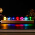 Macro view of seven colorful 3D laser engraved crystal balls on a wooden LED light base - Crystal Ball 7-Piece Set (JYSJ-SJQ-019) / Warm Light Plug-in Base