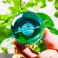 Close-up detail of 3D laser engraved Saturn crystal ball held against green foliage - Saturn (JYSJ-SJQ-019) / 60 Single Sphere