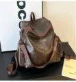 Dettaglio dello zaino marrone in ecopelle che mostra la trama e le tasche laterali. - Marrone
