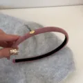 Détail d'un serre-tête en daim rose avec une délicate étiquette dorée 'Love' chic - Rose