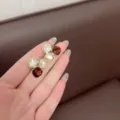 Close-up view of Maillard brown geometric crystal stud earrings held in hand for detail - Geometric Design (E3712) / Gold White
