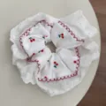 Detail view of the white lace scrunchie featuring a delicate cherry pattern and scalloped trim. - Scrunchie Style (FQ86173)