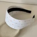 Primo piano di un cerchietto in tessuto bianco con piccoli fiori ricamati fini - Cerchietto Largo / 5cm / Fiore Beige