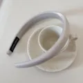 Primer plano de una diadema de satén gris claro acolchada sobre un platillo - Diadema de Seda Brillante / 2 cm de Ancho / Beige