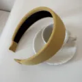 Detailed view of a mustard yellow wide ribbed padded headband styled on a white cup - 5cm Wide / Bright yellow