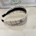 Vue détaillée d'un serre-tête à carreaux bleus avec un petit cœur et une étiquette tissu. - Serre-tête / Carreaux bleu et jaune