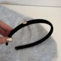 Gros plan d'un serre-tête en velours noir avec un élégant détail de plaque Love dorée - Noir