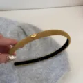 Détail d'un serre-tête étroit jaune moutarde avec une petite étiquette dorée 'Love' - Jaune
