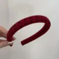 Detail view of a burgundy padded wide headband with black polka dots pattern held by hand - Polka Dot / 2.0cm / Red