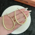 Large matte gold geometric oval hoop earrings displayed on a hand over a white plate - 4.4cm/6.4cm / Matte Gold