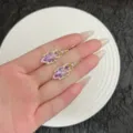 Elegante paarse kristallen bladoorbellen met goudkleurige zetting in de hand. - Creolen Sluiting Stijl / Paarse Hoepel