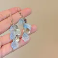 Primo piano di orecchini pendenti con petali blu e dischi d'argento testurizzati stile - Stile Nappina Martellata Petalo Blu (E4989) / Argento