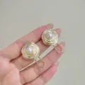 Detail showing elegant gold irregular spiral round earrings with white pearl inlay. - Clip-on Earrings / Gold