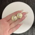 Detail view of irregular gold spiral stud earrings with elegant white pearl center. - Stud Earrings / Gold