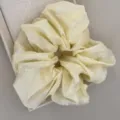 Gros plan d'un chouchou jaune crème avec broderie de nœuds blancs délicats. - Chouchou / Jaune