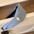 Détail rapproché d'un serre-tête large en velours bleu clair avec emblème de poney doré - Bleu