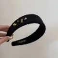 Gros plan d'un serre-tête noir pelucheux avec des breloques dorées en forme d'ours et de bourse - Design Cheval Chanceux / Noir