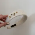 Vue détaillée d'un serre-tête en peluche blanche avec d'élégants charms dorés pour l'hiver - Design Cheval Chanceux / Beige