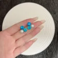 Detailed view of elegant blue rhinestone and white pearl stud earrings held in hand. - Exquisite Three-Star (E4934) / Silver Blue