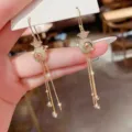 Close-up of festive gold fortune bag tassel earrings with cat eye stones and rhinestones - Cat Eye Tassel Style (E1623) / Gold