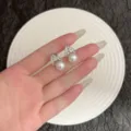 Vue détaillée de boucles d'oreilles en V argentées avec strass et perles blanches - Boucles d'Oreilles Clous en Perles et Strass en Forme de V Géométrique (E5006) / Argent