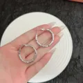 Detailed macro view of silver geometric textured hoop earrings held in hand - Bamboo Texture Hoop Style (E4797) / 3cm / Silver