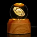 Dettaglio macro di una sfera di cristallo Saturno incisa al laser 3D su base in legno LED - Pianeta