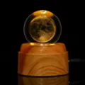 Dettaglio dell'incisione laser 3D della luna in una sfera di cristallo su base in legno LED - Terra