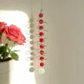 Gros plan d'un attrape-soleil en cristal en spirale avec des perles rouges au soleil. - Rouge vif